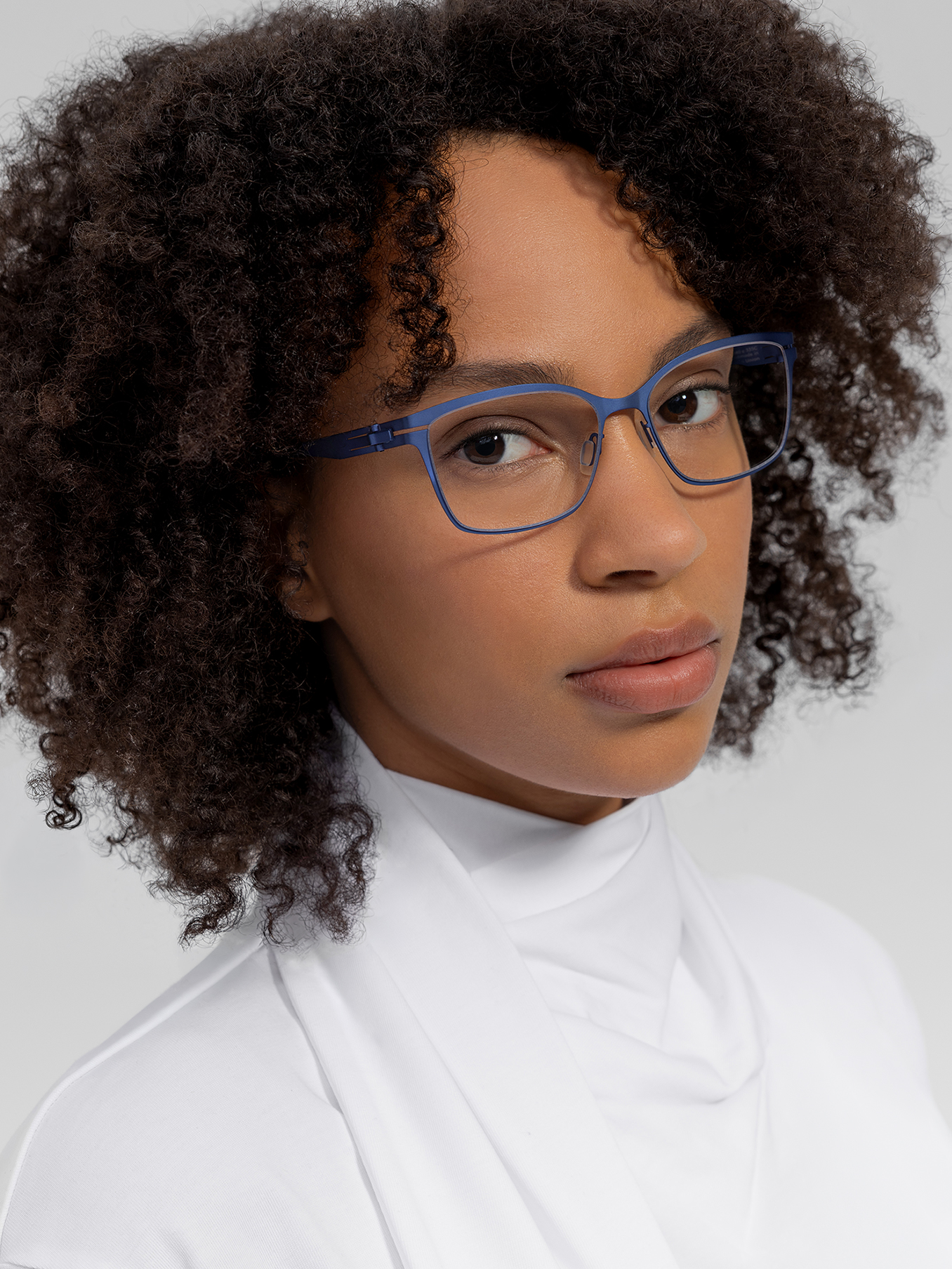 OVVO Optics portrait of a woman wearing blue angular optical glasses and a white high-neck top