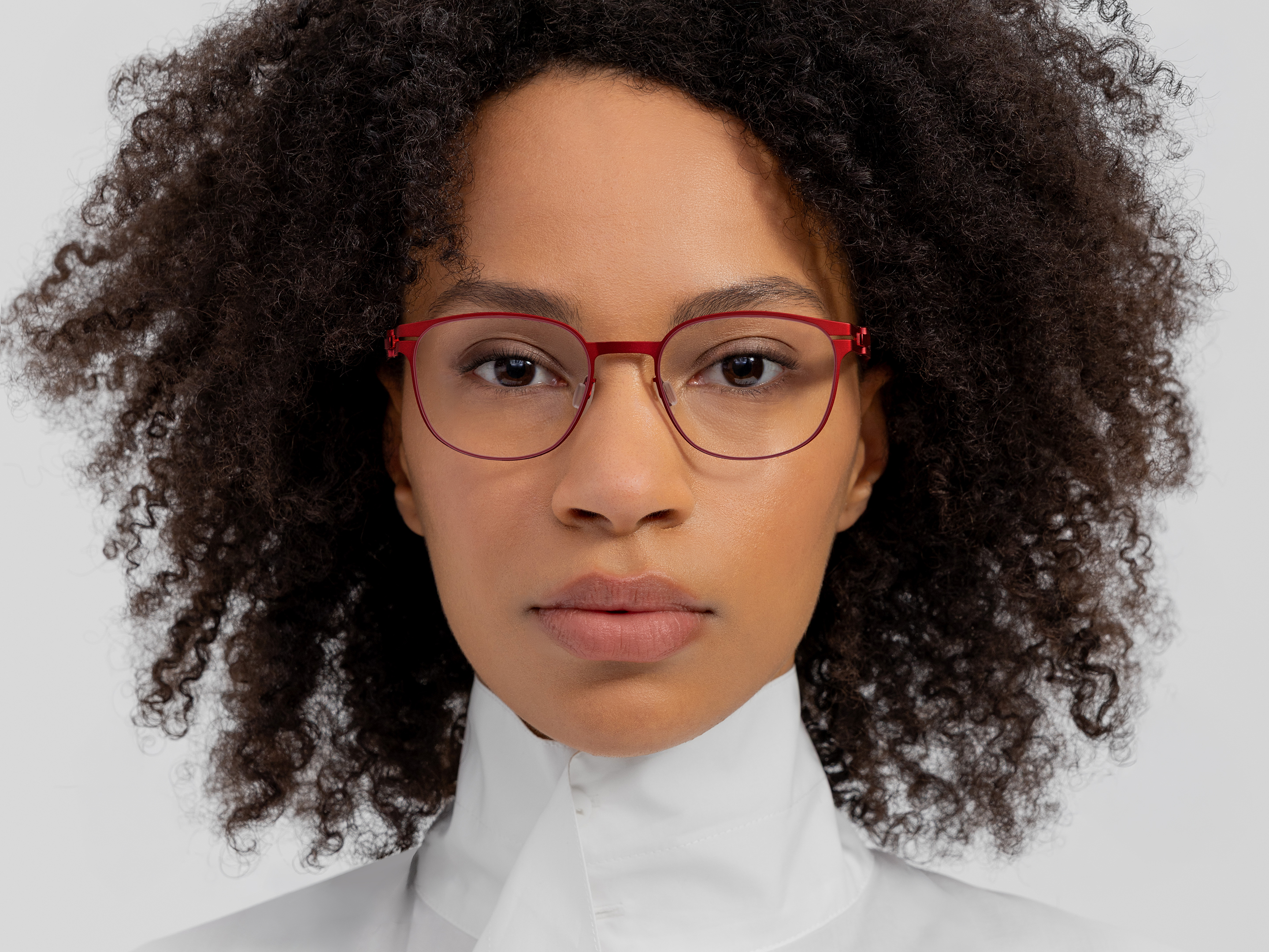 OVVO Optics front portrait of a woman wearing red round optical glasses and a white high-neck top