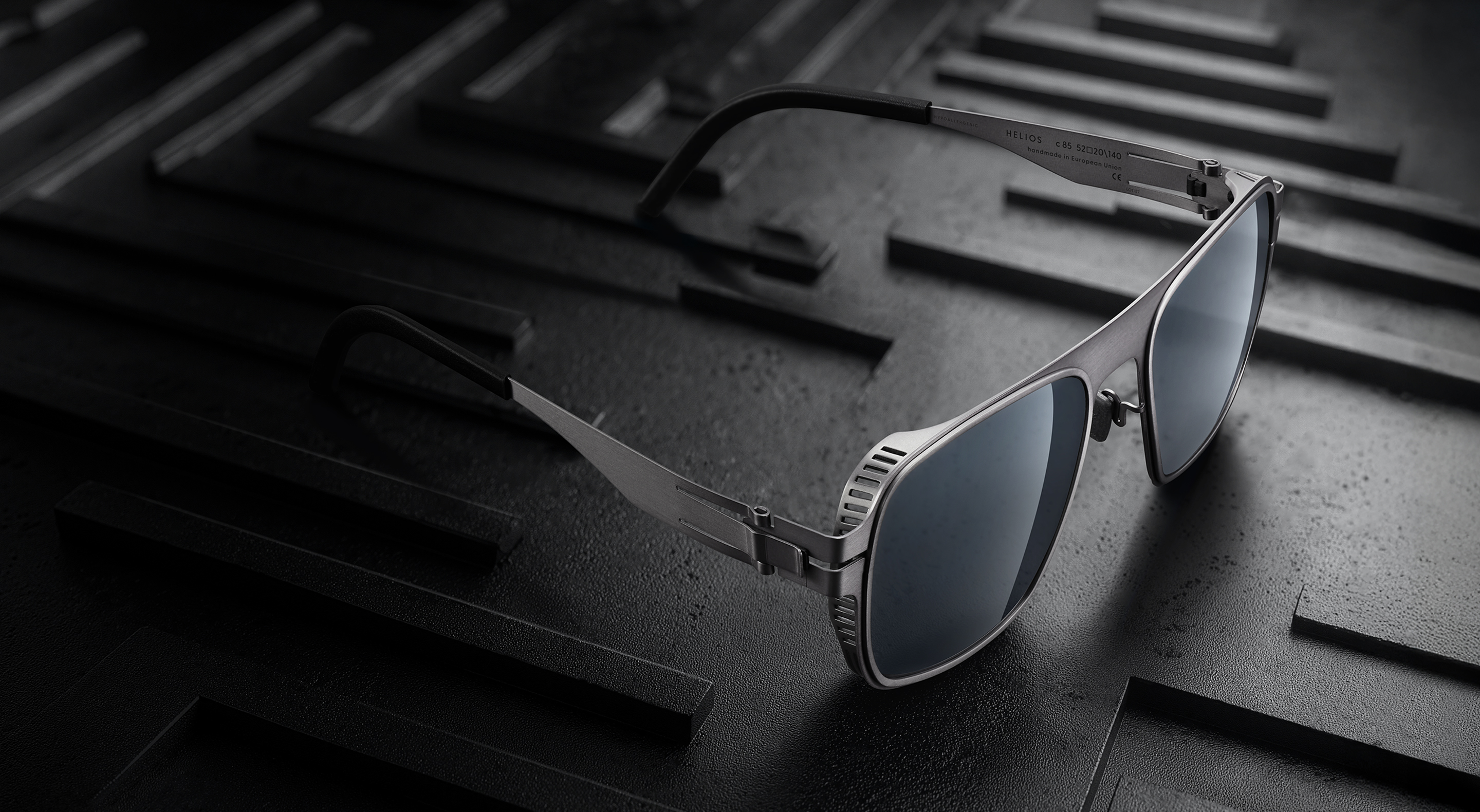 OVVO Optics Ti2 Helios titanium sunglasses on a dark precision-engineered surface
