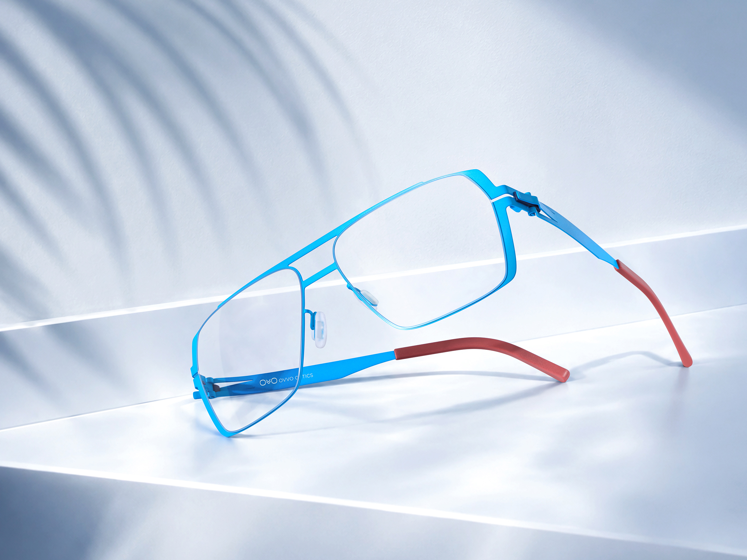 OVVO Optics pink geometric optical frame staged beside a clear acrylic arch in a studio product shot