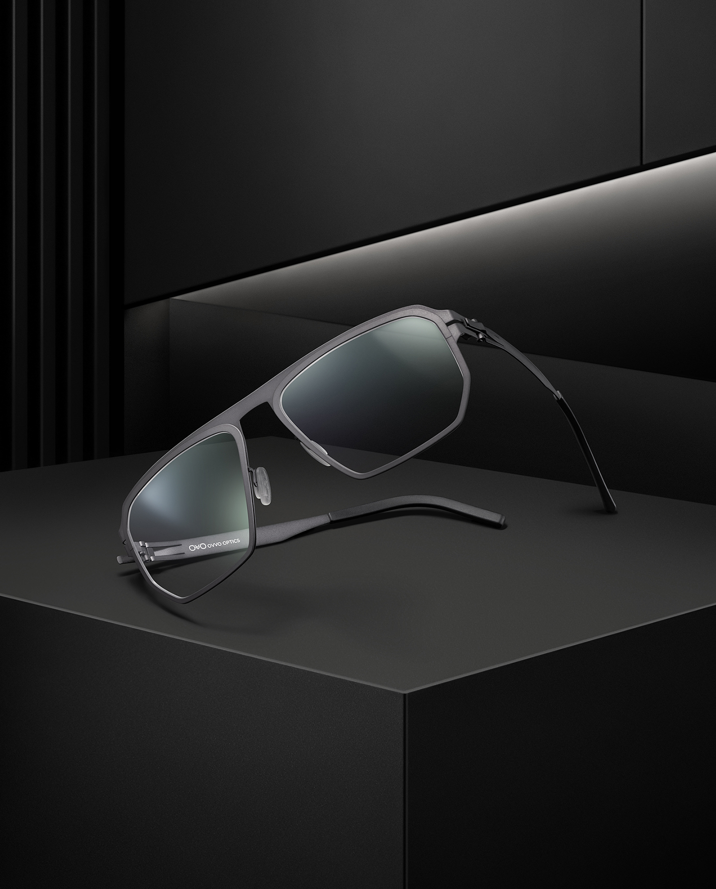 OVVO Optics Ti2 Expanded Kronos shield-shaped titanium sunglasses on a dark architectural set