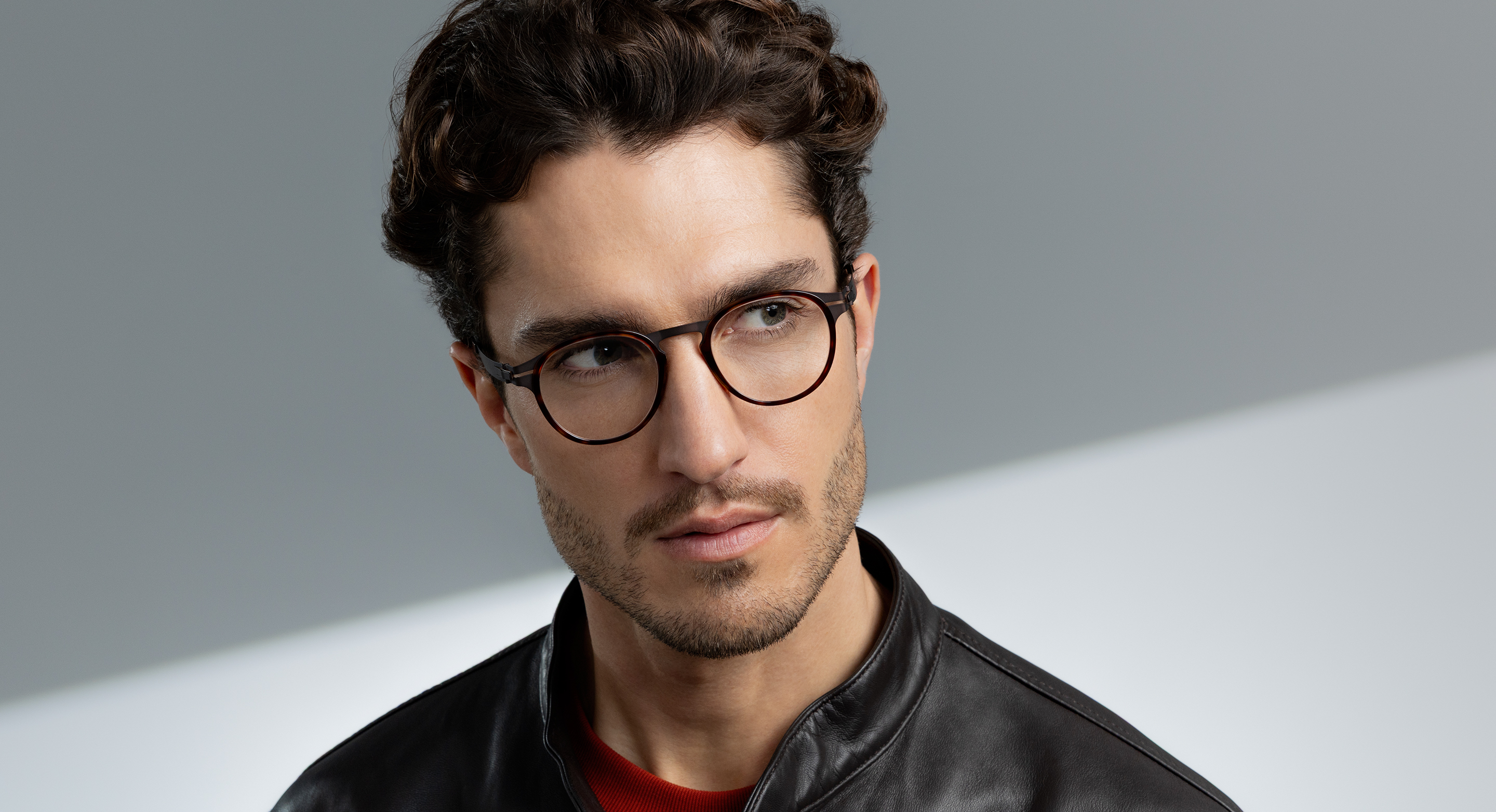 Man wearing OVVO Optics DUO Calvin round tortoiseshell eyeglasses and a black leather jacket against a gray background