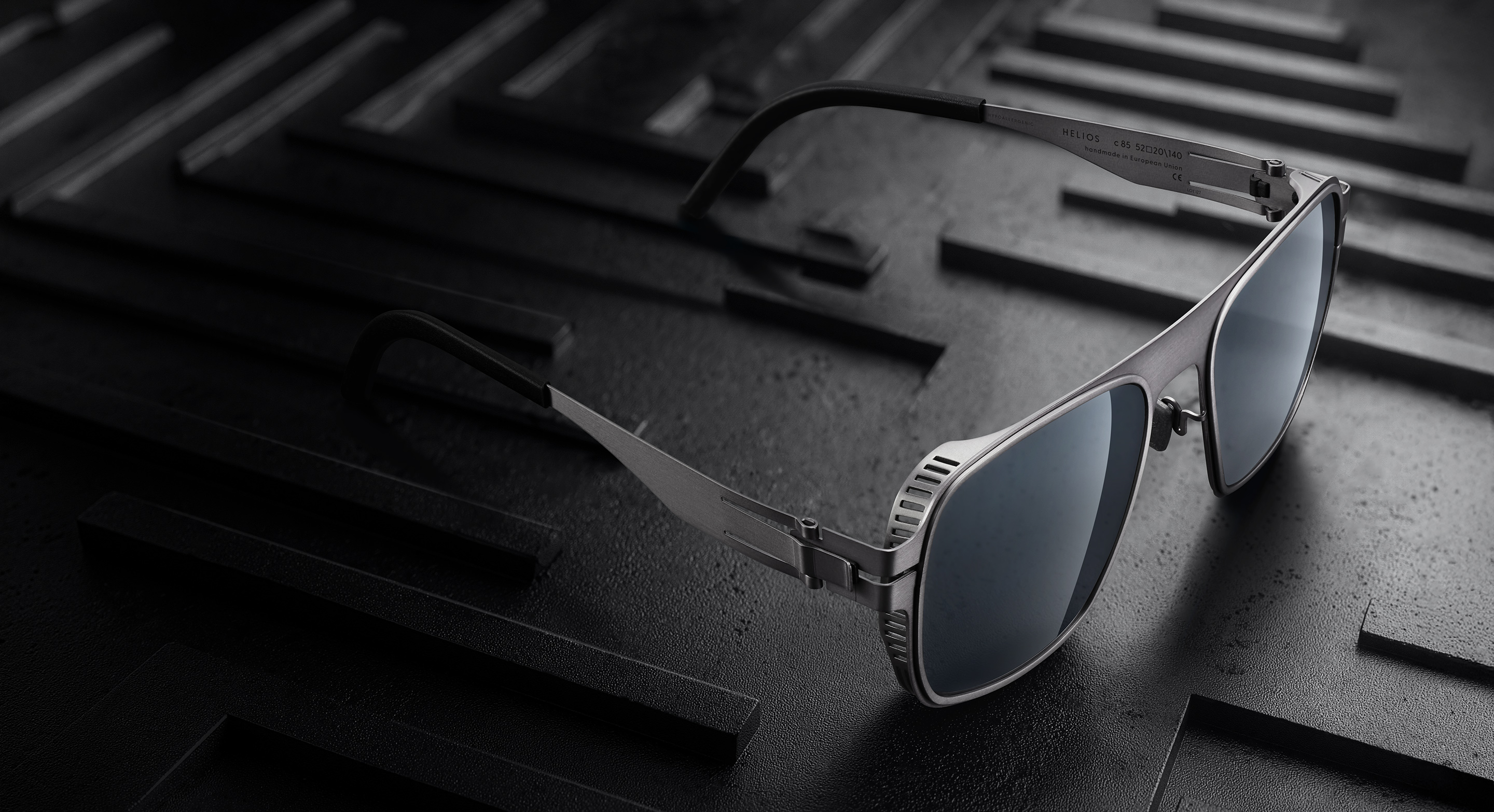 OVVO Optics Ti2 Helios sunglasses on a dark engineered surface